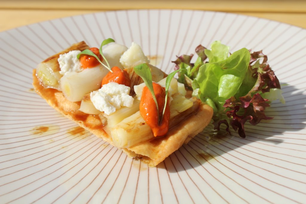 Coca de calçots, queso de cabra i escarola con vinagreta de romesco
