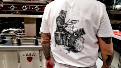 El lobo tocando la bateria está en las camisetaqs de los cocineros.