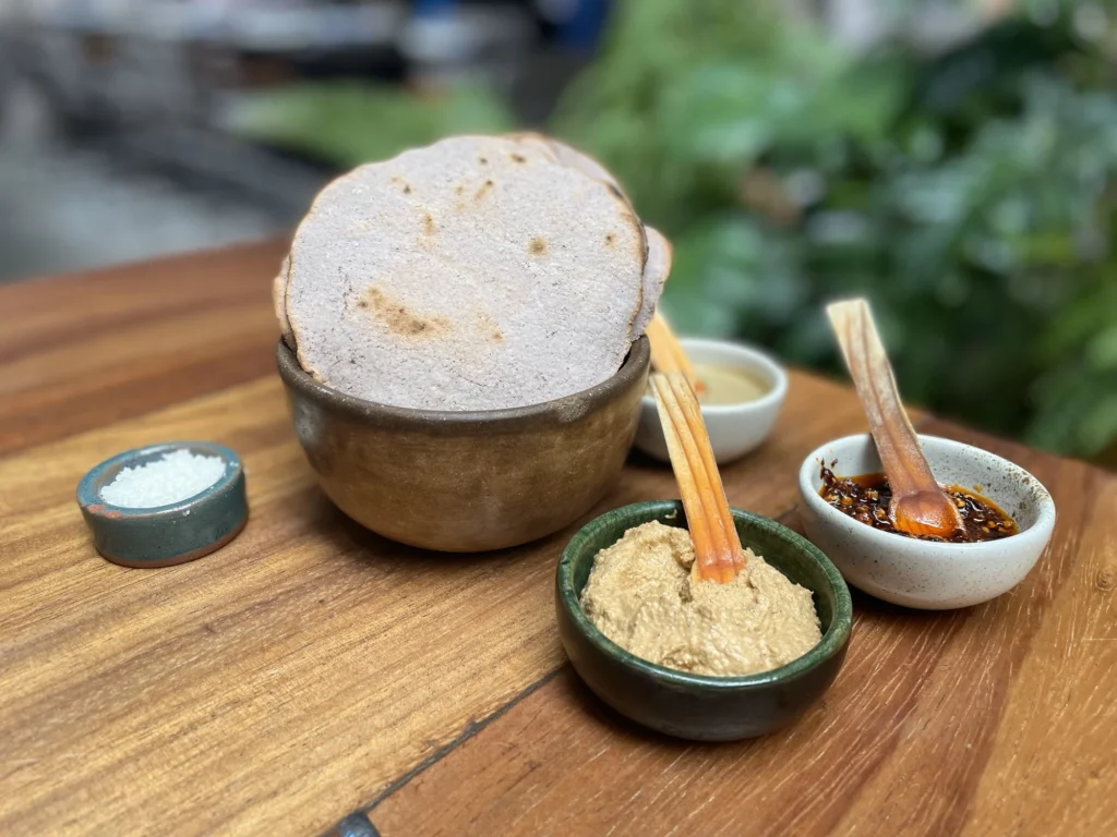 La imagen ilustra la factura artesanal de las tortillas y salsas de Maizajo