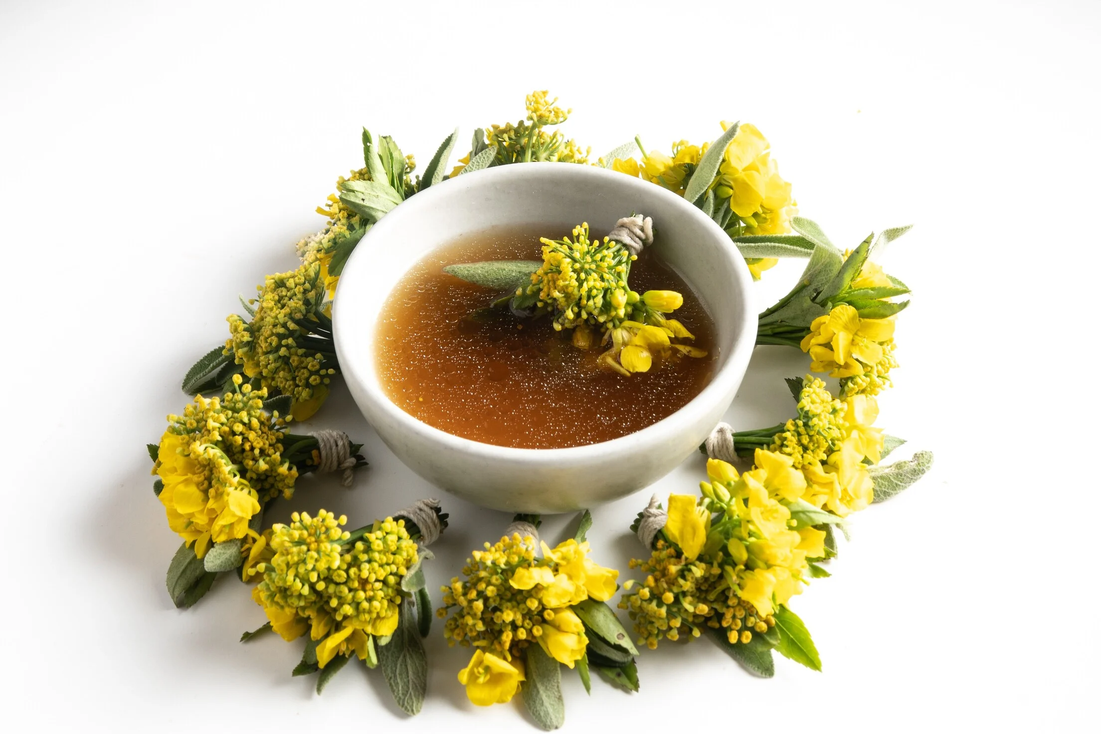 Caldo decorado con un bouquet de hierbas aromáticas y flores en El Chato, Bogotá.