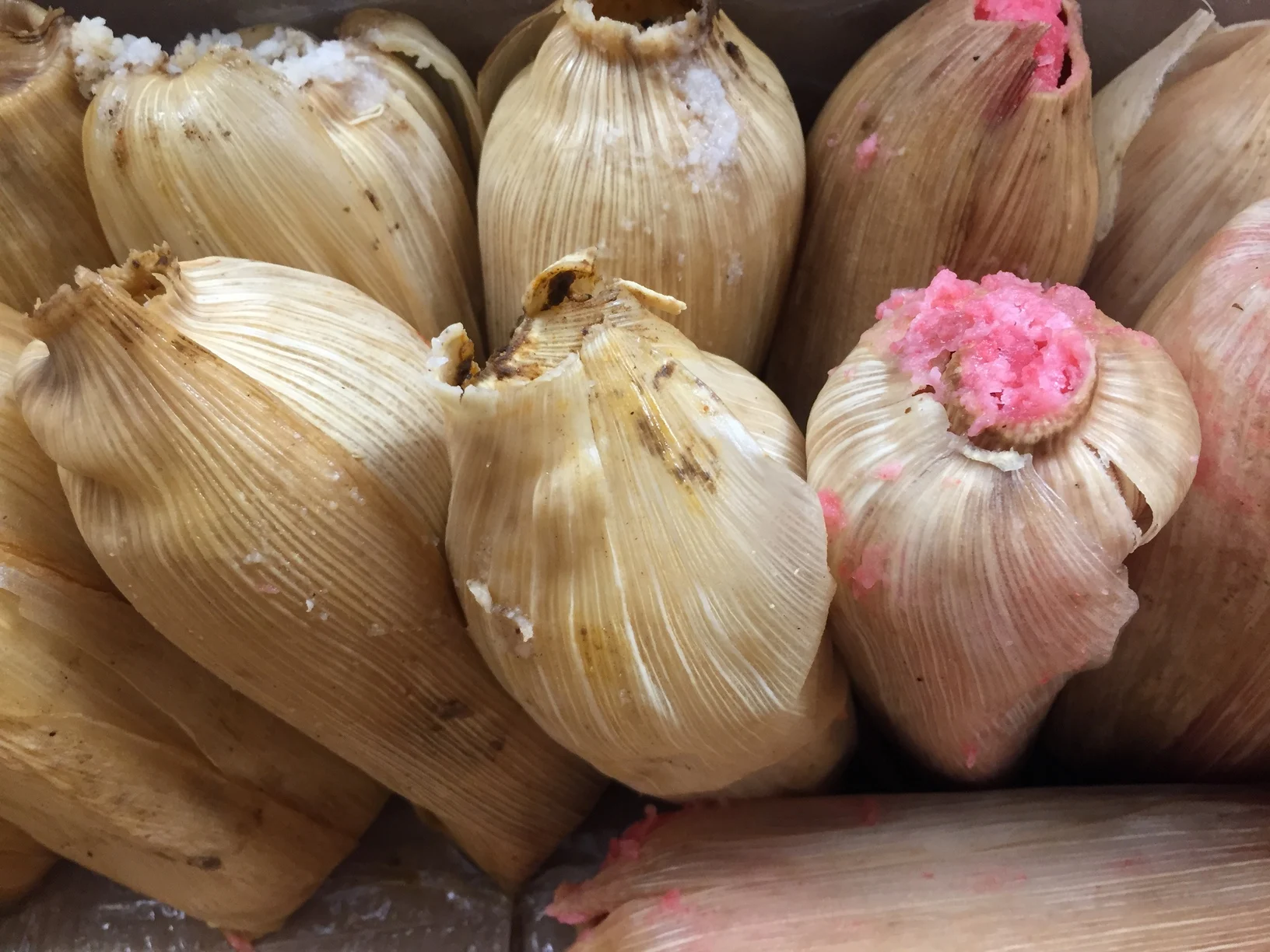 Tamales acomodados verticalmente en una vaporera para la cocción.