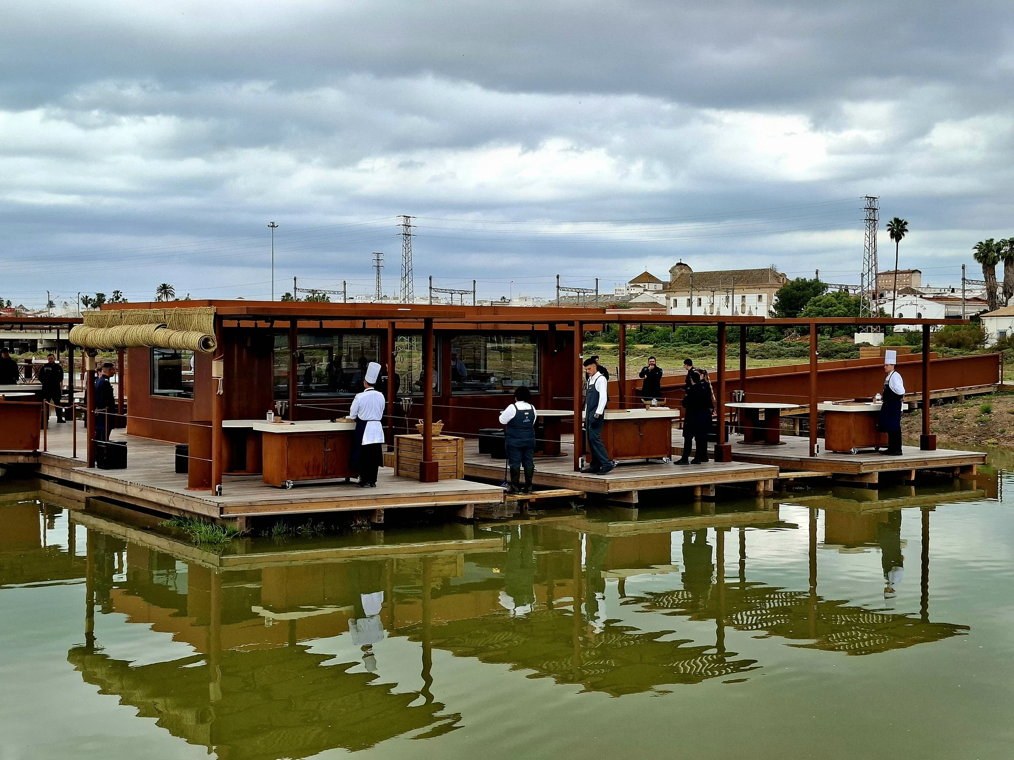 Aponiente 2026. Cocina flotante y mesas al aire libre preparadas para el aperitivo en la marisma.