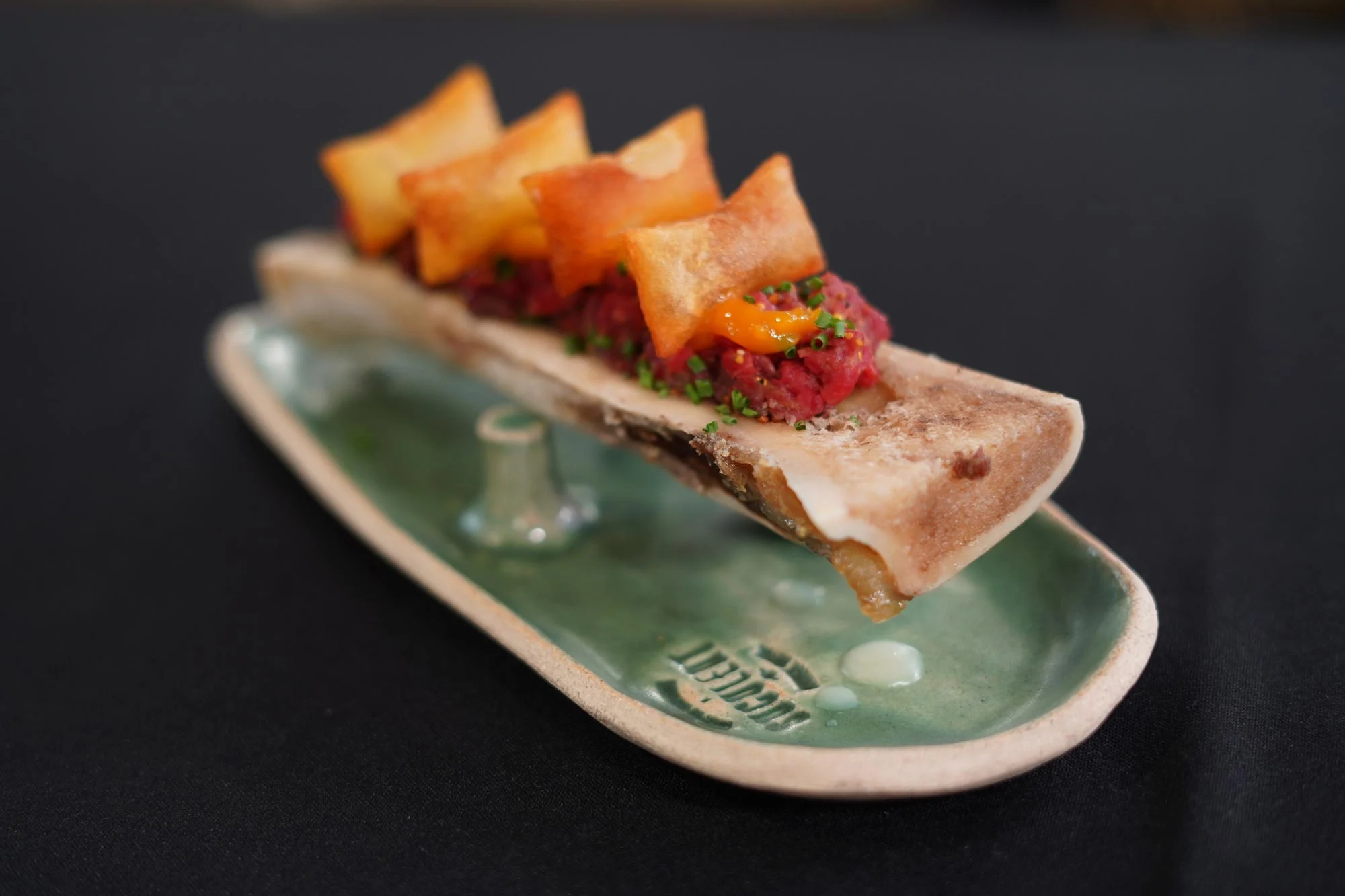 Steak tartare sobre tuétano asado con patatas suflés.
